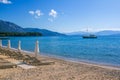 View of empty beach - wooden deck chairs and shade umbrellas near sea water Royalty Free Stock Photo