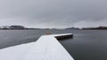 View of an empty bench in a wooden deck in the lake during winter Royalty Free Stock Photo