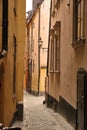 View of an empty, cobble street, alley between city buildings abroad in Stockholm, Gamla Stan. Narrow cobbled stone road Royalty Free Stock Photo