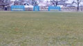 A view of an empty football field covered in grass with gates and stands for spectators, in winter during season