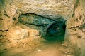 View into an empty medieval catacomb. Tunnel excavated in orange sandstone rock Royalty Free Stock Photo