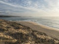 View of empty sand beach Praia do Farol at Vila Nova de Milfontes with view of ocean waves. Golden hour light