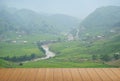 The view of the empty wooden table with a farmer village with a river running and fog on the mountain as a beautiful background Royalty Free Stock Photo