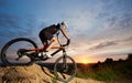 Athlete riding bike and rolling down hill against amazing sky background. Royalty Free Stock Photo