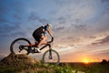 Athlete riding bike and rolling down hill against amazing sky background. Royalty Free Stock Photo