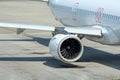 View of the engine of a passenger jet aircraft wing and fuselage with portholes on the platform parking