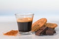 View of an espresso coffee surrounded by chocolate squares, cookies and brown sugar on a glass table