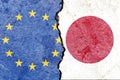 View of EU VS Japan national flags isolated on broken cracked concrete wall background