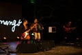 View of an evening and outdoor musical, cubo magico event, music concert with a woman playing the bass and a man playing the