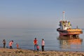 View of evening Persian Gulf with townspeople and towing boat.