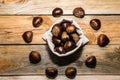 View of a fabric sack full of chestnuts surrounded by other chestnuts on a wooden background