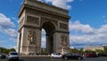 View of famous monument Arc de Triomphe with traffic on the surrounding road and crowd of tourists on sunny day in autumn.