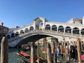 A view of the famous Rialto Bridge along the Grand Canal in Venice Italy.  Tourists and standing on the bridge Royalty Free Stock Photo