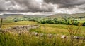 Fields and sheep on farm land in a valley with rain clouds