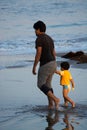 View of father and child are enjoying a leisurely stroll along a beautiful sandy beach Royalty Free Stock Photo