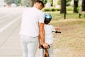 View of father helping son to ride on bicycle while kid sitting on bike