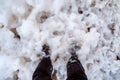 View of the feet drowning in the cold thick sea foam. White sea