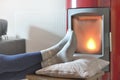 woman in socks relaxing in front of the heat of a wood stove