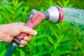 View on a female hand with a sprinkler watering a garden