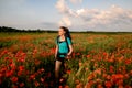 View of female tourist who walks on field of red poppies. Royalty Free Stock Photo