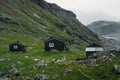 view of field with green grass and scattered stones against small rural houses, Norway, Hardangervidda