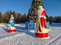 View of the figures of Santa Claus and the Snow Maiden near a snow-covered Christmas tree decorated with large glass balls and Royalty Free Stock Photo