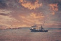 View of a fishing boat returning from the sea to land at sunset and a view of the small harbor, lighthouse Royalty Free Stock Photo