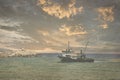 View of a fishing boat returning from the sea to land at sunset and a view of the small harbor, Royalty Free Stock Photo