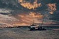 View of a fishing boat returning from the sea to land at sunset and a view of the small harbor, Royalty Free Stock Photo