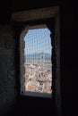 Florentine cityscape with red roofs and Giotto`s Campanile. View from a narrow window with iron grid of Palazzo Vecchio tower, Fl Royalty Free Stock Photo