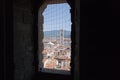 Florentine cityscape with red roofs and Giotto`s Campanile. View from a narrow window with iron grid of Palazzo Vecchio tower, Fl Royalty Free Stock Photo