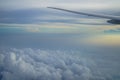 View of fluffy abstract white cloud and blue sky with airplane wing and sunrise light background from airplane window Royalty Free Stock Photo