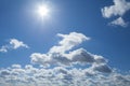 View of a fluffy clouds and midday sun in deep blue sky Royalty Free Stock Photo