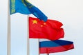 Fluttering flags of China, Russia, and Kazakhstan on a background of cloudy sky Royalty Free Stock Photo