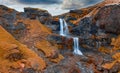 View from flying drone. Incredible evening view of nameless waterfall on Rauda river. Yellow hills on the southern coast of Icelan