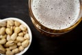 View of the foam of delicious beer in a glass and pistachios in a white bowl