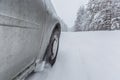 View focused on the car tire during in motion on snowy rural road during snowfall. Royalty Free Stock Photo