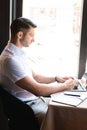 View of focused freelancer typing on laptop keyboard while sitting in cafe