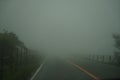 View of foggy roadway and fence while driving through local road on rainy and bad weather day on mount Aso area Royalty Free Stock Photo