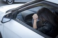 View form front window to a stressed or tired brunette girl in car lying on steering wheel. Female driver resting in Royalty Free Stock Photo