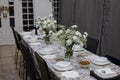 View of a formal dinner table with white tableware and flowers