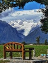 A view on the Fox Glacier on the South Island of New Zealand with a solid wooden seat on the foreground