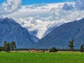 A view on Fox Glacier on the South Island of New Zealand with green farmland on the foreground