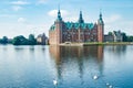 View of Frederiksborg castle with white swans on lake in Hillerod, Denmark