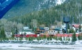 View of Freight train moving along the frozen river from Trans-Canada Highway with foggy mountains and a small village in the back
