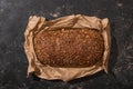 View of fresh baked loaf of whole grain bread in paper on stone black surface Royalty Free Stock Photo