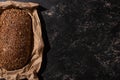 View of fresh baked loaf of whole grain bread in paper on stone black surface Royalty Free Stock Photo