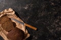 View of fresh cut loaf of brown bread with knife on paper on stone black surface Royalty Free Stock Photo