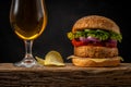 View of fresh tasty burger with glass of beer on wooden rustic table. Food background Royalty Free Stock Photo