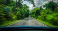 View from front of blue car on asphalt road and speed motion blur on highway in summer with trees forest at countryside Royalty Free Stock Photo